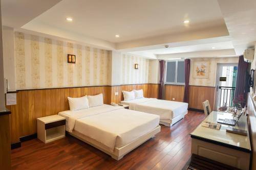 芽庄金雨2号酒店的酒店客房配有两张床和一张书桌