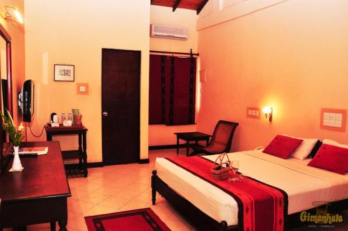 丹不拉吉曼哈拉酒店的配有一张床和一张书桌的酒店客房