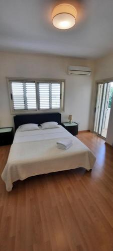 沃罗里尼Villa Larnaca Bay Resort的一间卧室设有一张大床,铺有木地板。