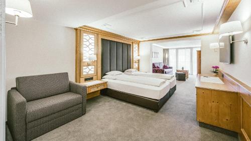 奥伯古格尔Gourmet & Wine Hotel Austria - 4 Sterne superior的配有一张床和一把椅子的酒店客房