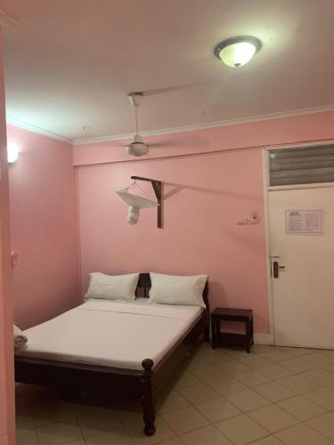 达累斯萨拉姆Kibodya Hotel Nkrumah的粉红色墙壁的房间里一张床位
