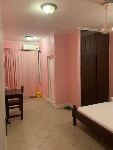 达累斯萨拉姆Kibodya Hotel Nkrumah的卧室设有粉红色的墙壁、一张床和一张书桌