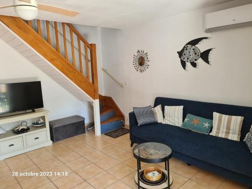 波尔蒂拉盖Villa tout confort dans résidence privée avec piscine à 500m de la plage - Climatisation, WIFI, parking的客厅设有蓝色的沙发和楼梯。