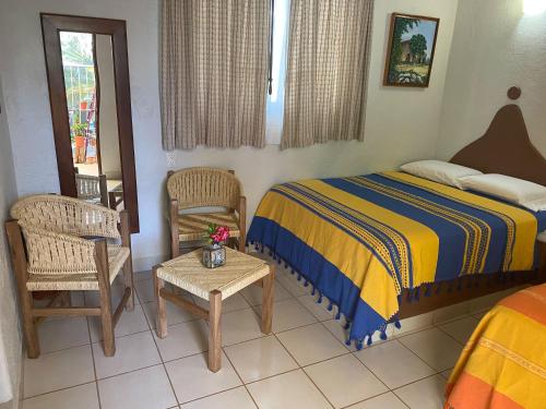 埃斯孔迪多港Zandoyo Bed & Breakfast的一间卧室配有一张床、两把椅子和一张桌子