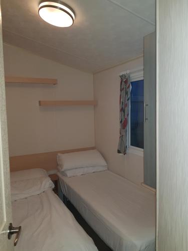 滨海克拉克顿Beautiful 3-Bedrooms Static Caravan Holiday Home的小房间设有两张床和窗户