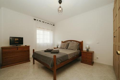 阿玛考德佩拉Apartamento Cristina - Próximo da praia的一间卧室配有一张带电视的床和梳妆台。