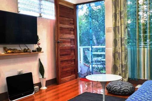 DaetCozy TinyHouse near SM City Daet的客厅配有电视、桌子和窗户。