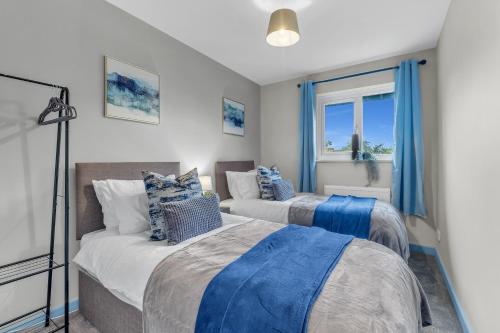 米尔顿凯恩斯MK 2-Bedroom Contractor's Gem, 5 beds, sleeps 6, free parking的配有蓝色窗帘的客房内的两张床