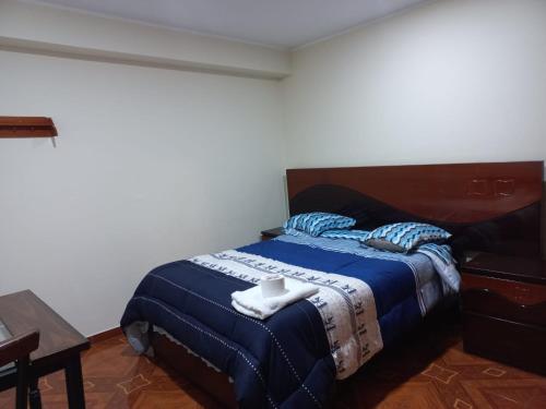 瓦努科KISWAR的一间卧室配有一张带蓝色毯子的床