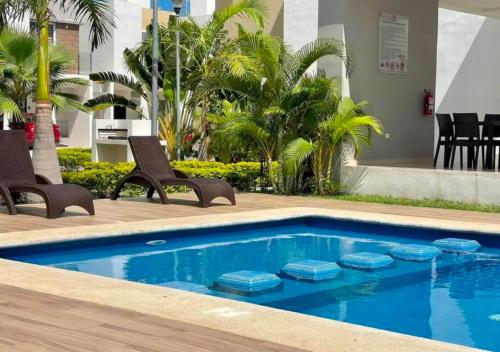 坎昆Casa familiar en condominio privado cerca de playa的一个带两把椅子和一张桌子的游泳池