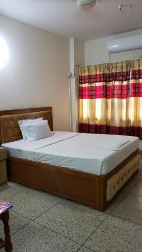 达卡Taz Garden House的一间卧室配有一张带窗帘的大床