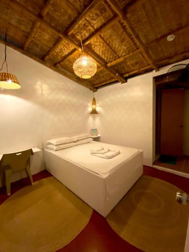 TibiaoKasa Raya Inn的卧室配有白色的床和椅子