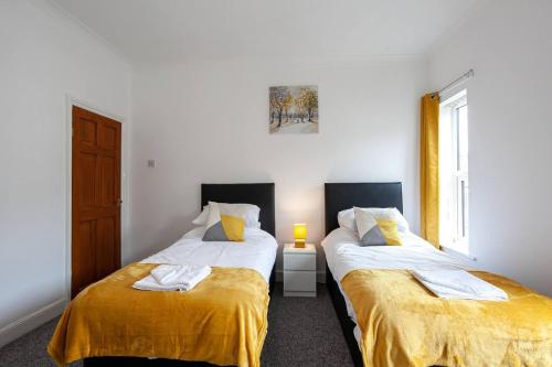 特伦特河畔斯托克Inspired Stays- City Centre- Spacious 4 Bed House!的一间卧室配有两张带黄床单的床