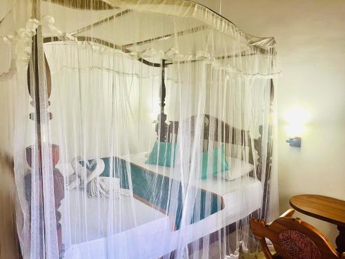 阿鲁特伽马Charly Villa的卧室内的天蓬床和白色窗帘
