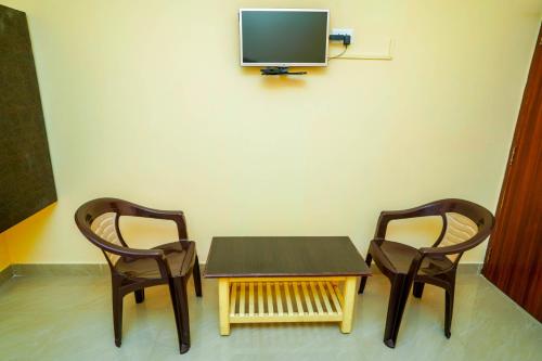 蒂鲁帕蒂Ssunshhine residency (NEW)的两把椅子和一张桌子,墙上有一台电视机