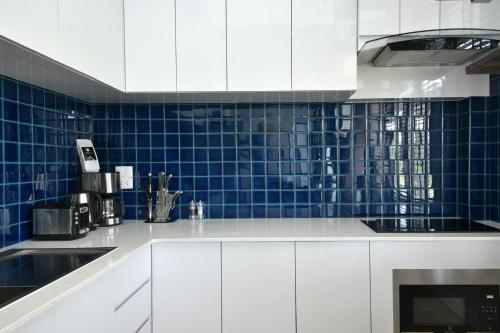 Bang KrasopGreen Lung Pool Villas Bangkok的厨房配有白色橱柜和蓝色瓷砖墙壁
