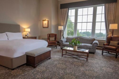 利兹Oulton Hall Hotel, Spa & Golf Resort的酒店客房配有一张床、一张沙发和椅子。