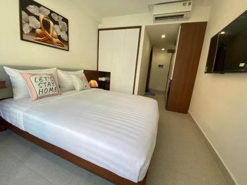 胡志明市Saigon Hotel & Apartment的卧室配有一张大白色床和电视。