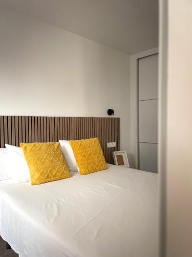 格拉纳达H&H Suite El Mirlo的卧室配有白色床和2个黄色枕头