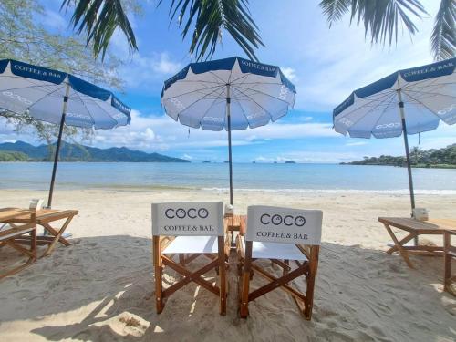 象岛Coconut Beach Resort, Koh Chang的海滩上的几把椅子和遮阳伞
