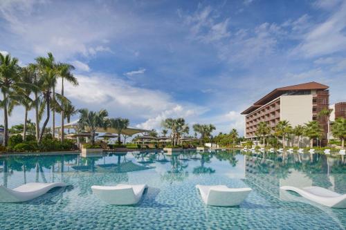 三亚三亚天丽湾凯悦酒店的一座带白色椅子的游泳池和一座建筑