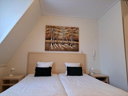 代尔夫宰尔博文格罗宁根餐厅酒店的一间卧室设有两张床,墙上挂着一幅画