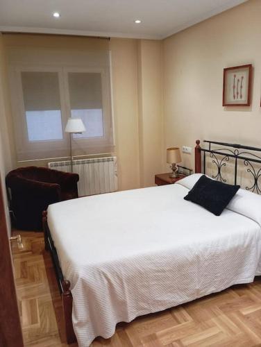 卢安科El rinconín de Luanco的卧室配有一张白色大床和一把椅子