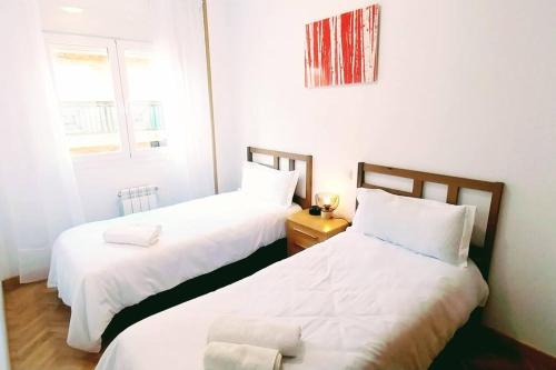 曼萨纳雷斯-埃尔雷亚尔Manzanares Getaway的小客房内的两张床,配有白色床单