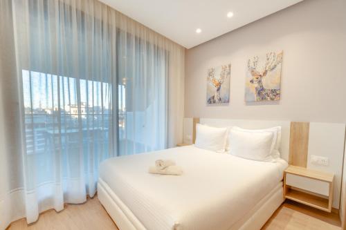 丹吉尔Luxury Apartments的卧室设有白色的床和大窗户