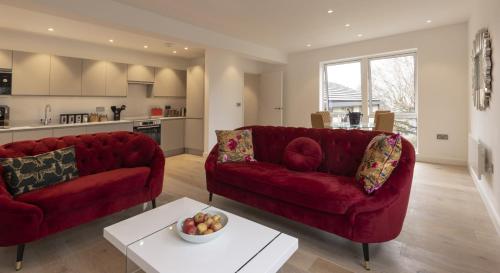 巴斯Charlecote House的客厅配有两张红色的沙发和一张桌子