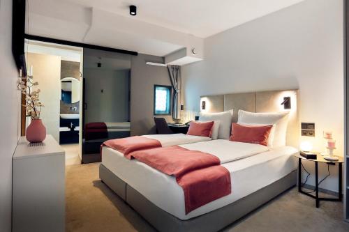 卢布尔雅那The Hotel Ljubljana的卧室配有带红色枕头的大型白色床