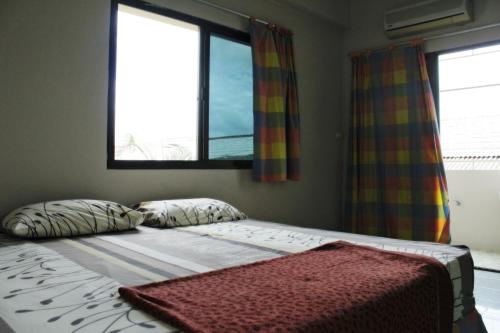 合艾永生禅公寓的卧室内的一张床位,设有两个窗户