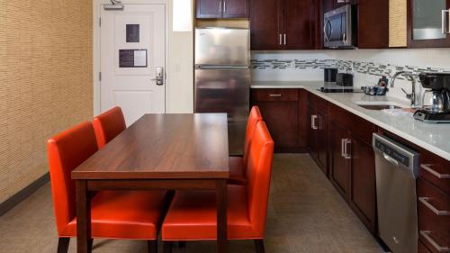 杰克逊维尔Residence Inn by Marriott Jacksonville South Bartram Park的厨房配有木桌和橙色椅子