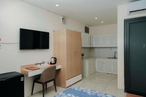 Tây NinhARINA HOTEL的厨房配有书桌和墙上的电视。