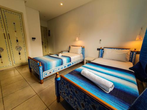 舍夫沙万Hotel Marrakech的一间客房内配有两张床的房间