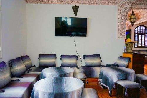 舍夫沙万Hotel Marrakech的配有桌椅和平面电视的客房