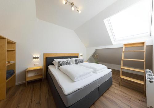 明登Pension Sonne Appartements的卧室配有一张带白色床单的大床和窗户。