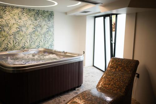 斯雷姆斯卡米特罗维察HOTEL GRACIAN的带浴缸的带椅子的房间