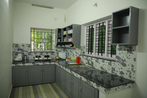 特里凡得琅LA CASA THE HOMESTAY的厨房配有灰色橱柜和黑色台面