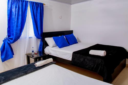 RuiosucioSecretos del Eden的一间卧室设有两张床,窗户配有蓝色窗帘