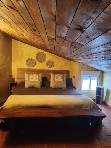 比利亚埃尔莫萨德尔里奥Buhardilla rústica muy acogedora的一间卧室设有一张带木制天花板的大床