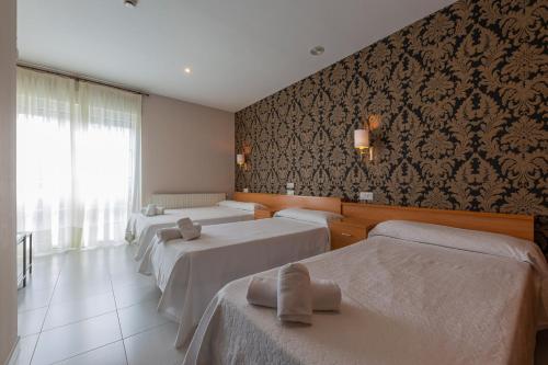 Mazaricos卡萨菊里奥酒店的酒店客房设有三张床和窗户。