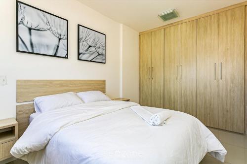 弗洛里亚诺波利斯Apto lindo e confortável em frente à UFSC RVR0506的卧室配有一张白色大床和木制橱柜。