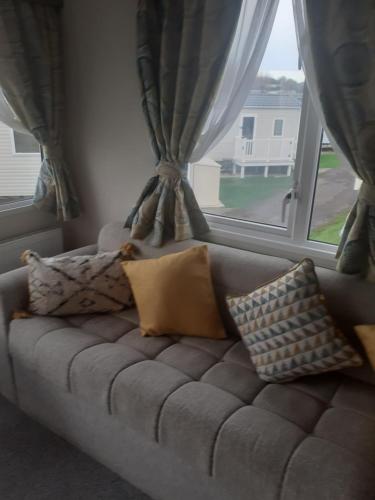 韦茅斯Littlesea Haven Weymouth的靠窗前的沙发,配有枕头