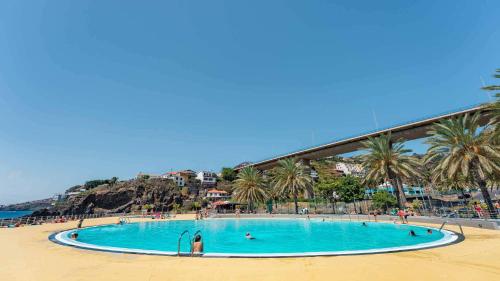 加乌拉Casa do Mundo Madeira的棕榈树海滩上的大型游泳池