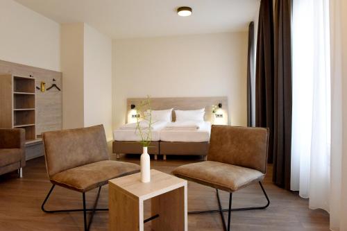 埃滕海姆DiMas Hotel Ettenheim - Rust的酒店客房,配有一张床和两把椅子