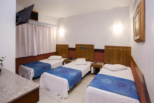 库里提巴Rede Andrade São Francisco的酒店客房设有三张床和电视。