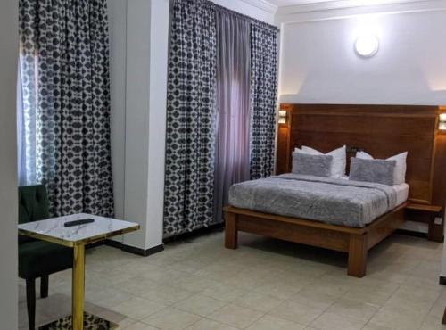 DschangJAD HOTEL Dschang的一间卧室配有一张床、一张桌子和窗帘