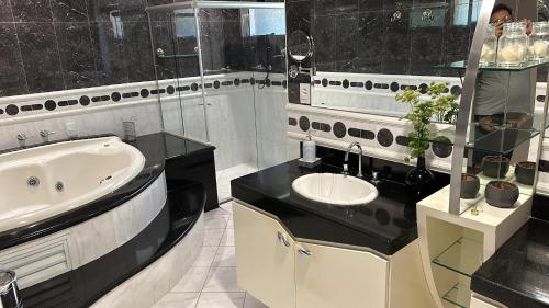 坎皮纳斯Job&Joy Business Hostels的黑白浴室设有水槽和浴缸。