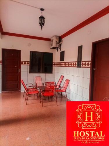 圣克鲁斯Hostal Plaza de la Concordia的一间设有红色椅子、桌子和标志的房间